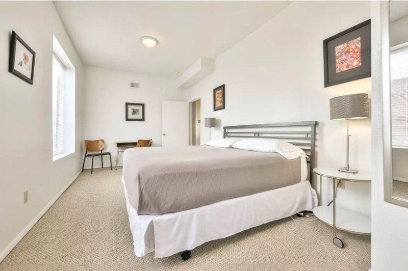 Bedroom with a metal-frame bed, desk and tall window