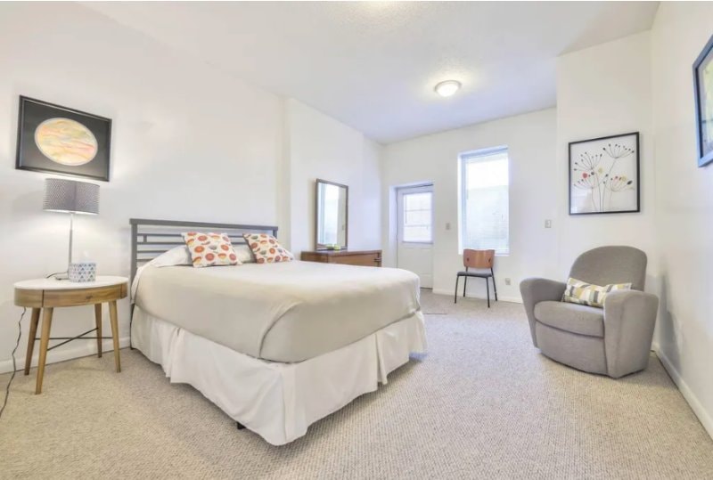 Second bedroom with bed, armchair and a door with a window