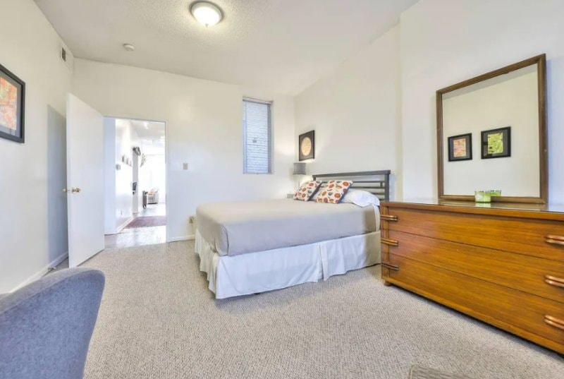 Second bedroom with wood dresser and mirror, doorway to the hall