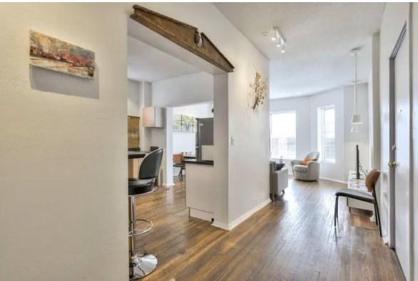 Entry hall with hardwood floors, breakfast bar stools and a view into the living room