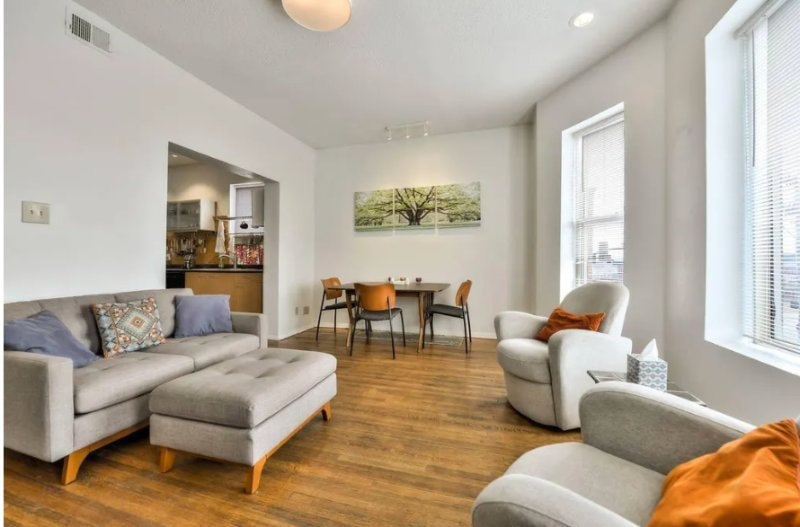Living and dining area with sofa, dining table for four and tall windows